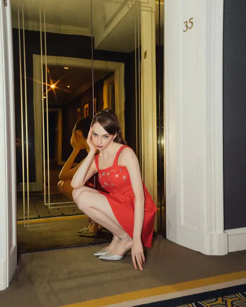 Creator posing in a red dress by a mirrored doorway