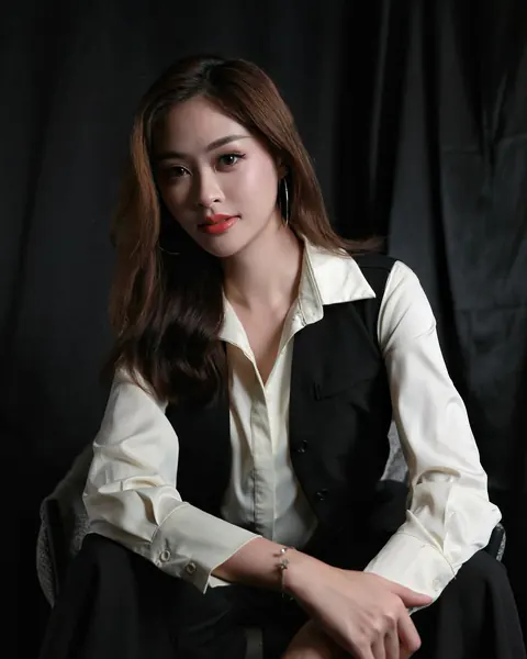 Creator in a cream collared shirt and black vest against a dark backdrop