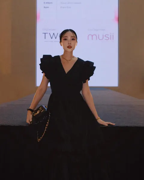 Creator in a black dress in front of a MUSII event backdrop